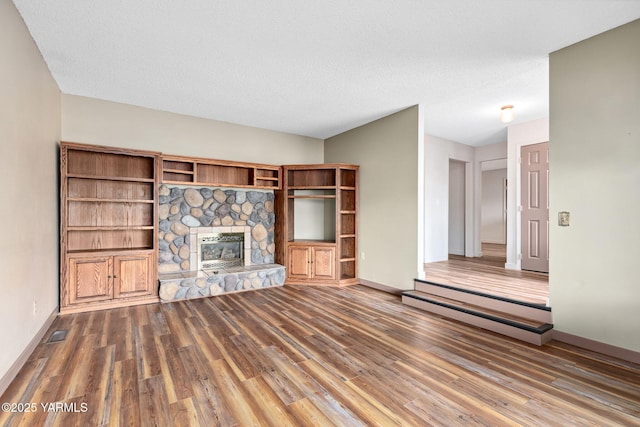 3204 Clinton Way, Yakima, WA 98902 - unfurnished living room with wood finished floors, a stone fireplace, and a textured ceiling