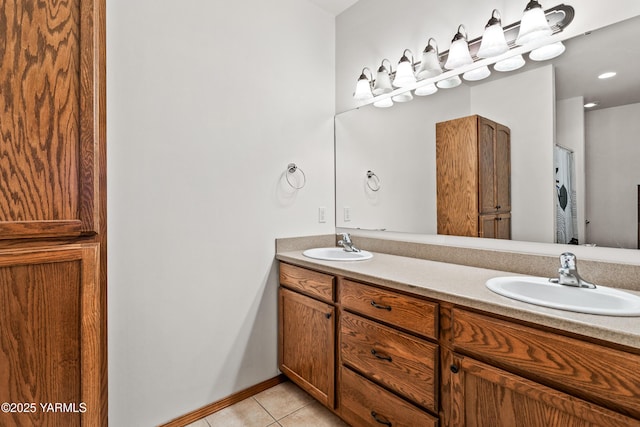 bathroom with baseboards, double vanity, a sink, and tile patterned floors