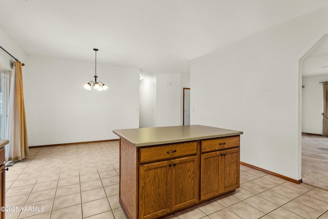 kitchen with a center island, brown cabinets, decorative light fixtures, light tile patterned floors, and light countertops