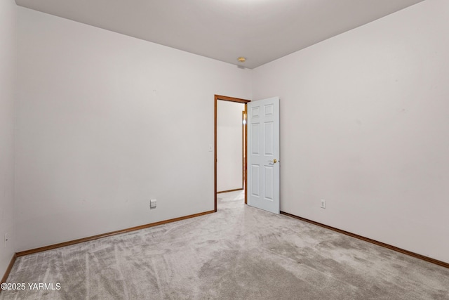 empty room with baseboards and light colored carpet