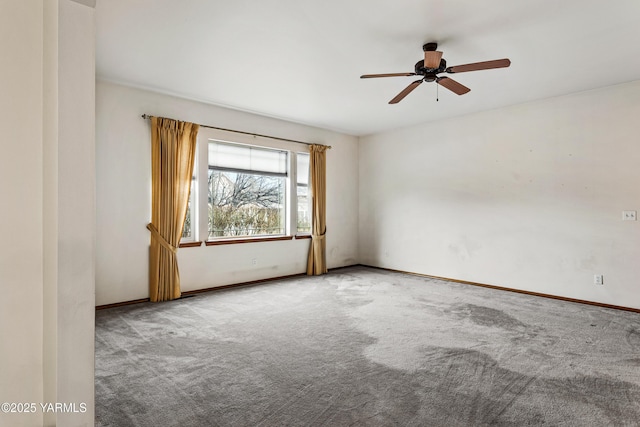 carpeted spare room featuring ceiling fan and baseboards