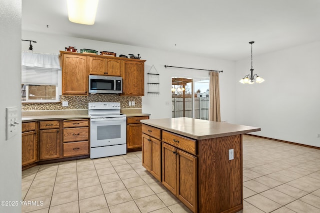 kitchen with electric stove, stainless steel microwave, a center island, decorative light fixtures, and light countertops