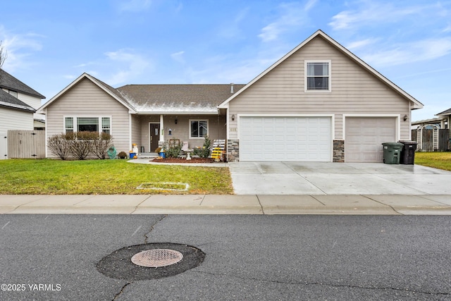 view of front of house with concrete driveway, fence, a garage, stone siding, and a front lawn