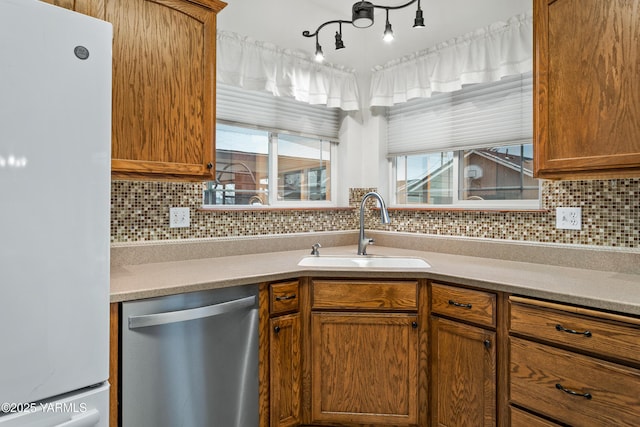 kitchen with dishwasher, light countertops, a sink, and freestanding refrigerator