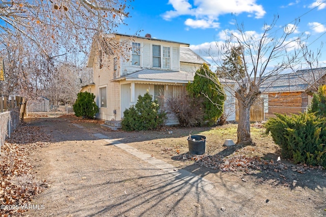 view of front of home featuring driveway, a chimney, and fence