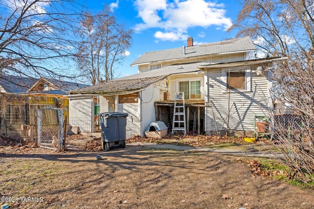 rear view of property with fence and a chimney