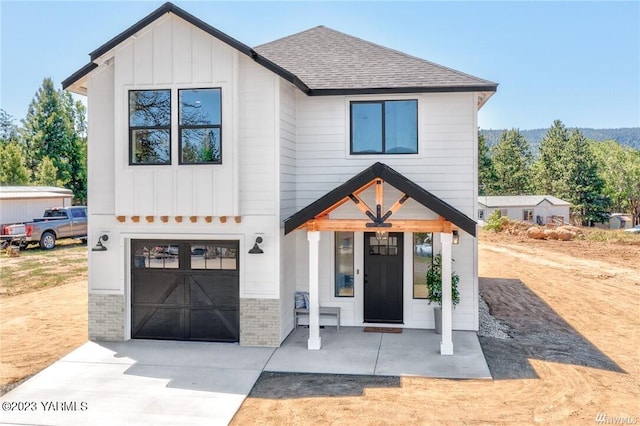 modern farmhouse style home featuring an attached garage, brick siding, a shingled roof, concrete driveway, and board and batten siding