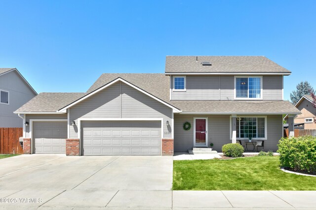 5807 W Whatcom Ave, Yakima, WA 98903 - view of front of house with an attached garage, driveway, a porch, a shingled roof, and brick siding