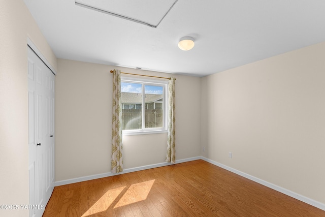 unfurnished bedroom featuring wood finished floors, a closet, and baseboards