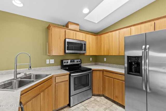 kitchen with appliances with stainless steel finishes, a sink, vaulted ceiling, a skylight, and light countertops