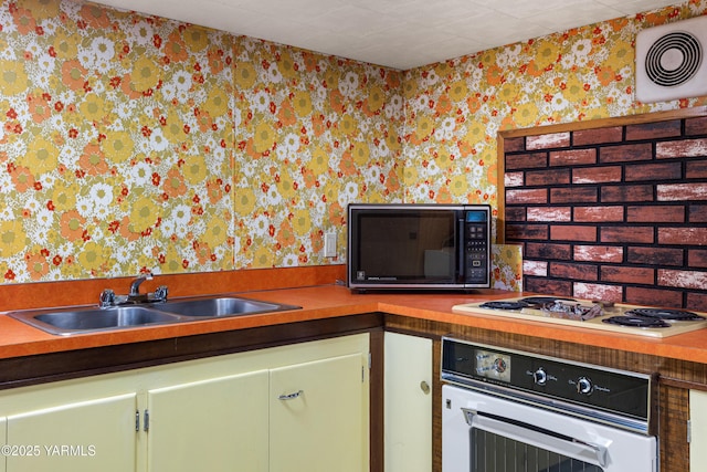 kitchen with white appliances, a sink, visible vents, and wallpapered walls