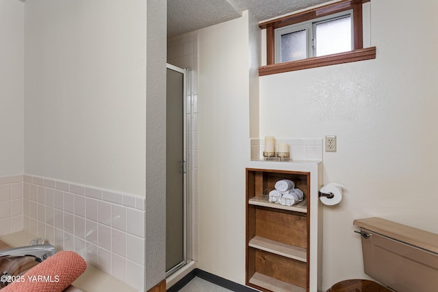 full bathroom with a stall shower, a textured ceiling, and toilet