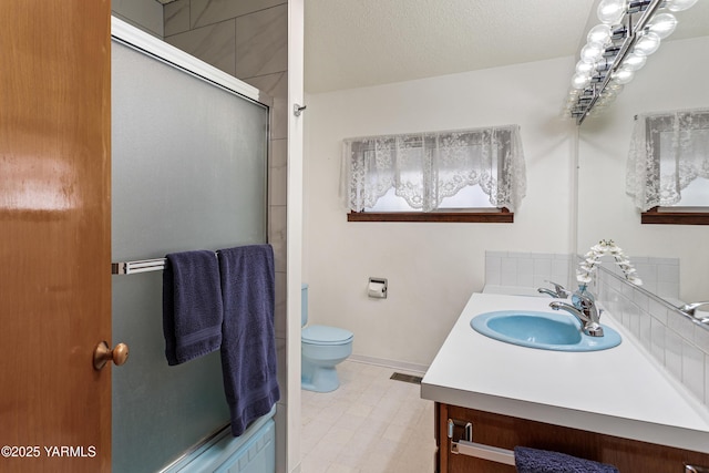 bathroom featuring a shower with door, visible vents, toilet, vanity, and a textured ceiling