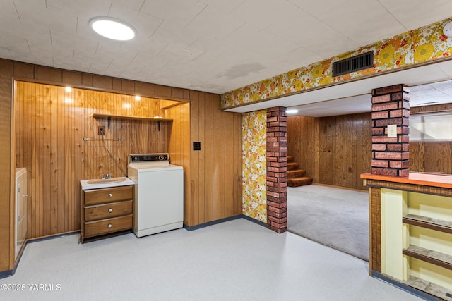 basement featuring visible vents, a sink, washer / dryer, baseboards, and stairs