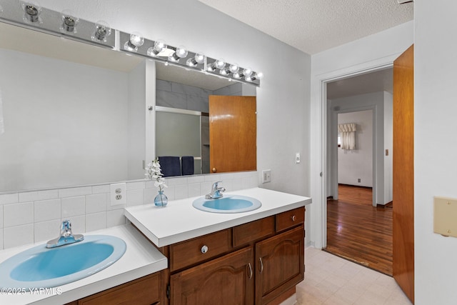 bathroom featuring a stall shower, decorative backsplash, tile patterned floors, a textured ceiling, and vanity