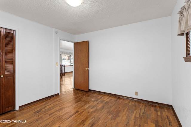 unfurnished bedroom with a closet, wood-type flooring, a textured ceiling, and baseboards