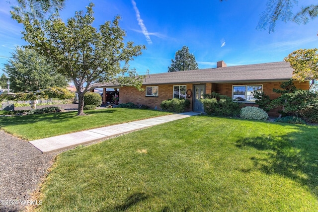 ranch-style home with brick siding, a chimney, and a front yard