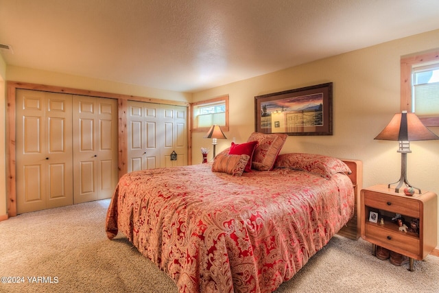 bedroom with visible vents, multiple closets, and light colored carpet