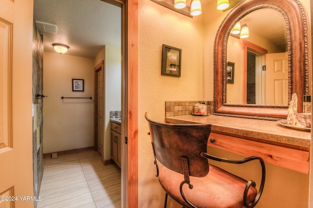 bathroom with tile patterned floors, a textured ceiling, and vanity