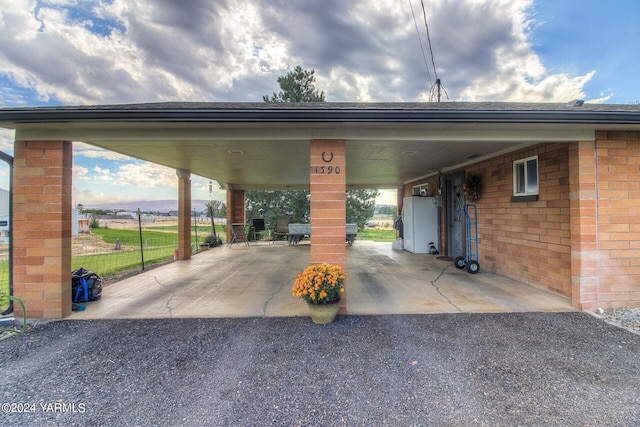 view of parking / parking lot with fence, aphalt driveway, and a carport