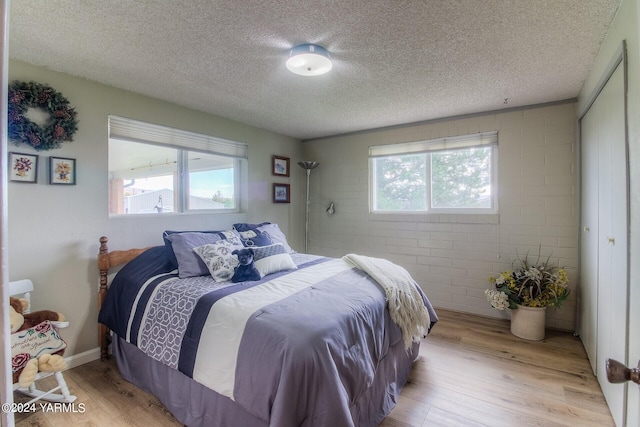 bedroom with light wood-style floors, multiple windows, and a textured ceiling