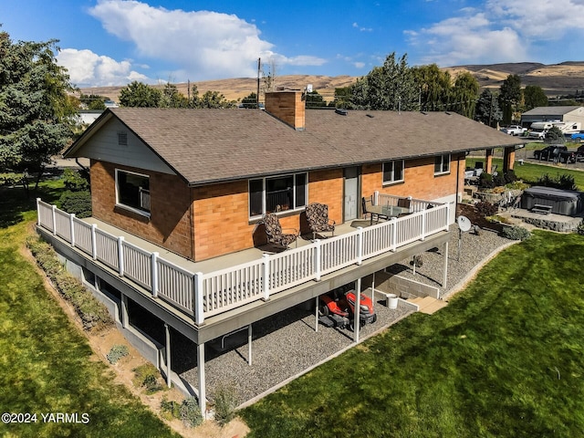 rear view of property with roof with shingles, a lawn, a chimney, and a wooden deck