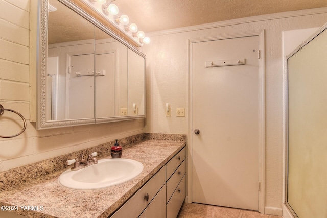 bathroom with tile patterned flooring, ornamental molding, a textured ceiling, and vanity