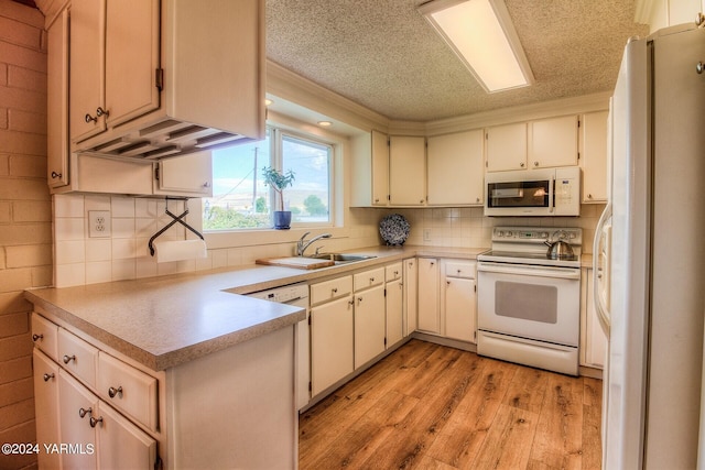 kitchen featuring light countertops, white appliances, backsplash, and a sink