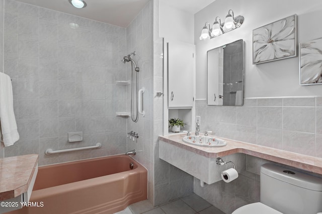 full bathroom with shower / tub combination, a sink, tile patterned flooring, tile walls, and toilet