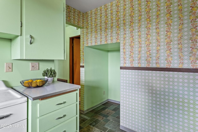 kitchen with stone tile flooring, washer and clothes dryer, green cabinets, and light countertops
