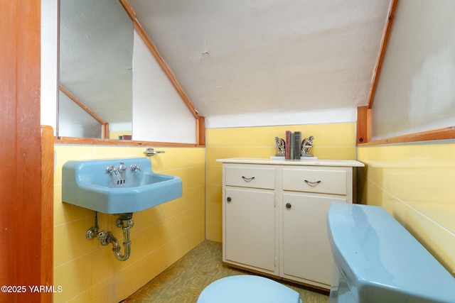 half bath with vaulted ceiling, a sink, and toilet