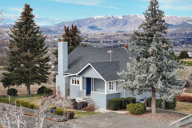 view of front of house with a garage, roof with shingles, a chimney, and a mountain view