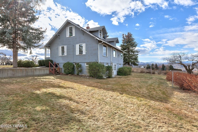 view of property exterior featuring a lawn, a chimney, and fence