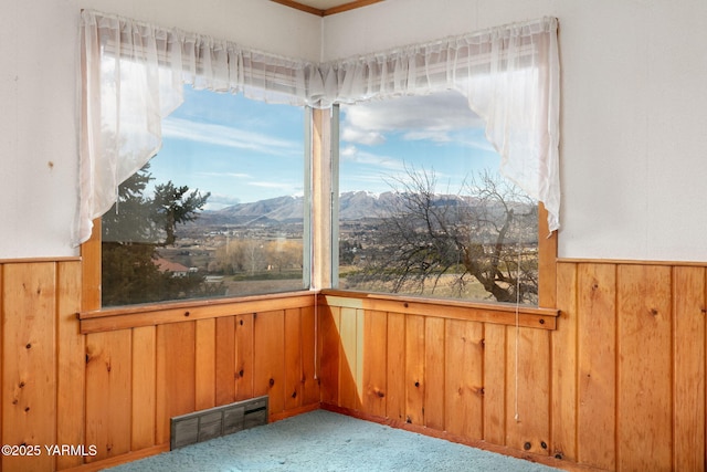 carpeted spare room with wooden walls, visible vents, a mountain view, and wainscoting