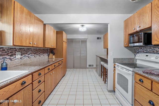 kitchen with light tile patterned flooring, white electric range oven, stainless steel microwave, tasteful backsplash, and visible vents