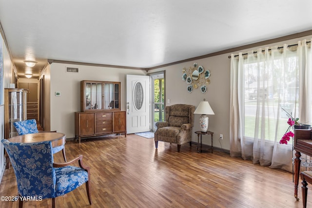 entryway featuring crown molding, baseboards, wood finished floors, and visible vents