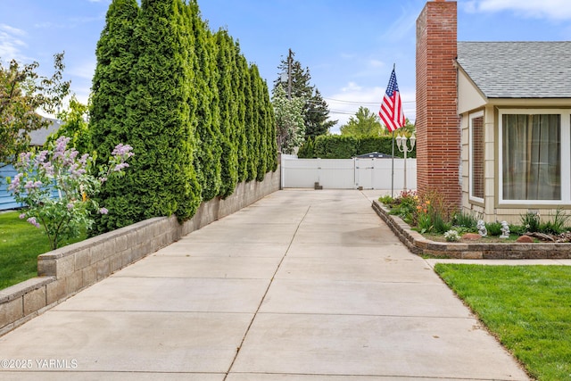 view of home's exterior with a gate, fence, a chimney, and a shingled roof