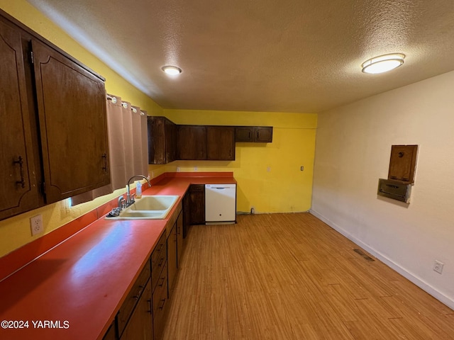 kitchen with visible vents, light wood-style floors, dark brown cabinetry, a sink, and dishwasher