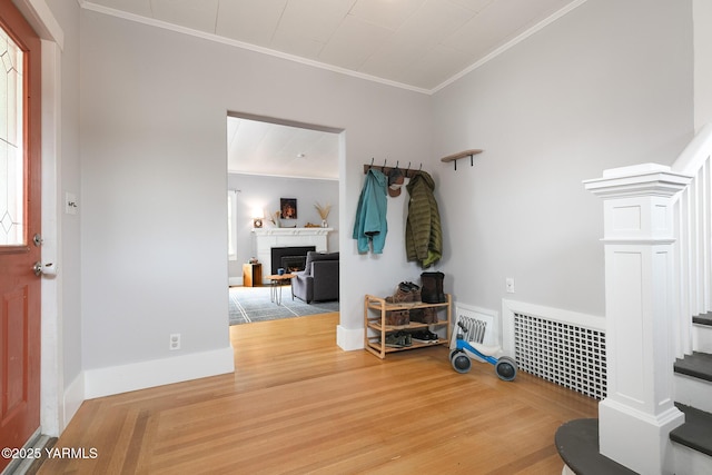 entryway featuring a warm lit fireplace, visible vents, wood finished floors, and crown molding