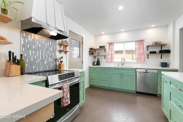 kitchen with green cabinets, appliances with stainless steel finishes, wall chimney range hood, and open shelves