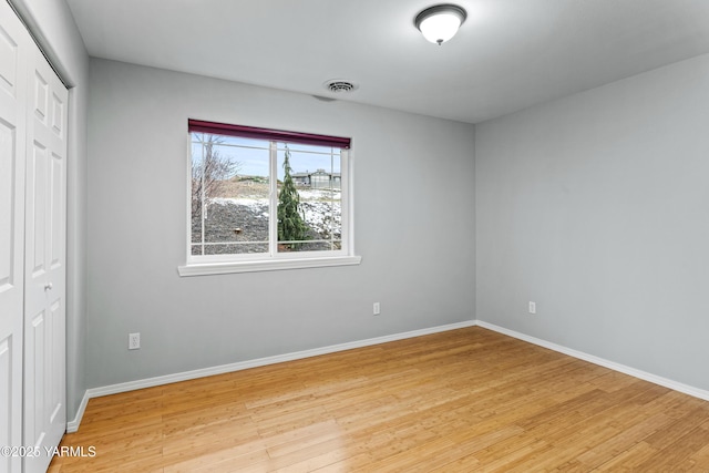 unfurnished bedroom with light wood-style floors, baseboards, visible vents, and a closet