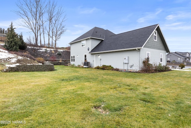 view of home's exterior with roof with shingles, central AC unit, and a yard