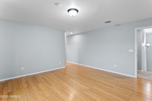 empty room featuring baseboards, visible vents, and light wood-style floors