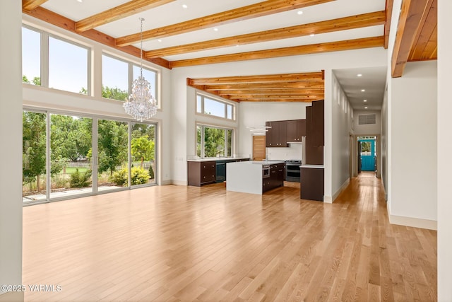 8 N 96th Ave, Yakima, WA 98908 - unfurnished living room with a chandelier, beamed ceiling, light wood-style flooring, recessed lighting, and a towering ceiling