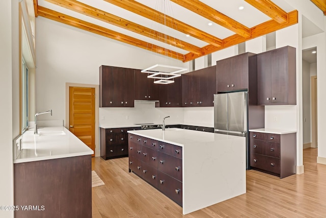 8 N 96th Ave, Yakima, WA 98908 - kitchen with beamed ceiling, light wood-style flooring, light countertops, dark brown cabinetry, and a towering ceiling