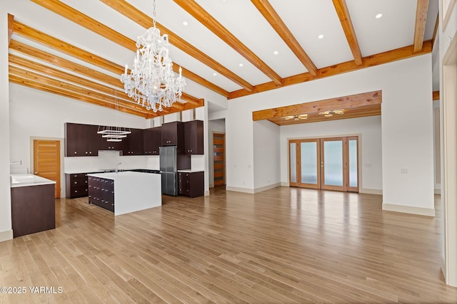 8 N 96th Ave, Yakima, WA 98908 - unfurnished living room with a chandelier, beam ceiling, light wood-style floors, a high ceiling, and recessed lighting