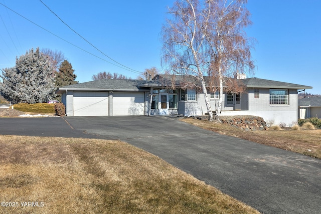 ranch-style home with a garage, driveway, and a front lawn