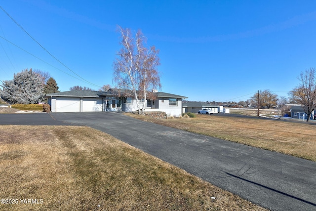 ranch-style house with an attached garage, aphalt driveway, and a front yard