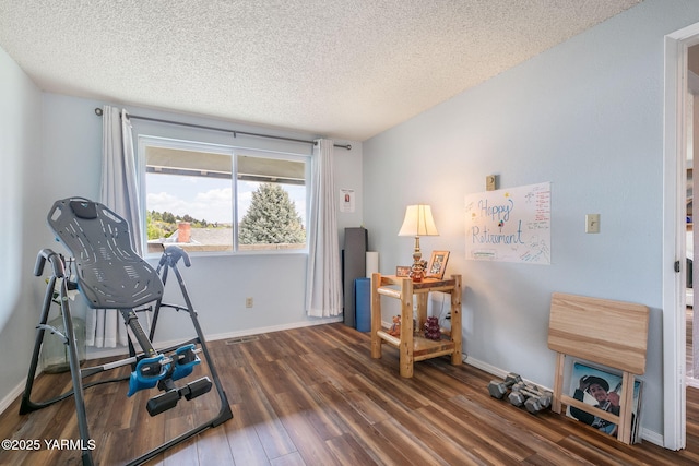 interior space with baseboards, visible vents, a textured ceiling, and wood finished floors