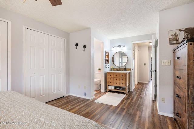 bedroom featuring a sink, baseboards, dark wood-style floors, and a textured ceiling
